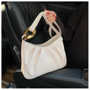 Detail of off-white pleated cloud bag with large golden metal buckle in car setting