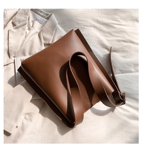 Minimalist deep brown matte leather tote bag styled on beige fabric background