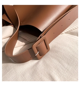 Detail of wide leather shoulder strap with a square buckle on a brown tote bag
