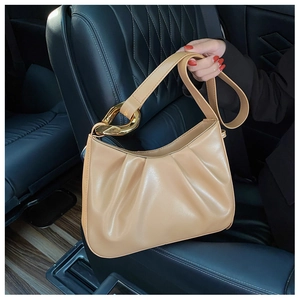 Detail of khaki pleated cloud bucket bag featuring luxury gold chain hardware on car seat
