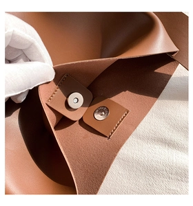Detail of the magnetic buckle closure and stitching on the brown leather tote bag