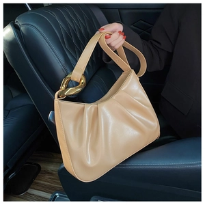 Detail of pleated apricot cloud bag with luxury gold metallic ring buckle on car seat