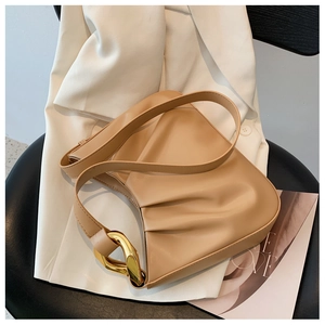 Detail of light beige pleated cloud bag with stylish large gold metal buckle on a chair