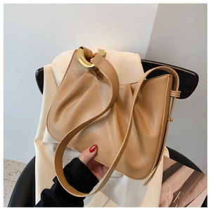 Detail of camel leather pleated bag showing oversized gold metal ring hardware on the strap