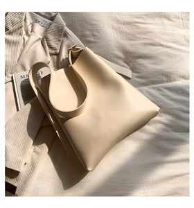 Detailed texture of off-white large capacity tote bag on warm beige fabric