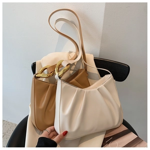 Detail of ruched cloud bags in cream and caramel with chunky gold chain hardware