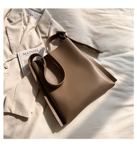 Detail of the high-capacity coffee leather tote bag with wide shoulder strap on blazer