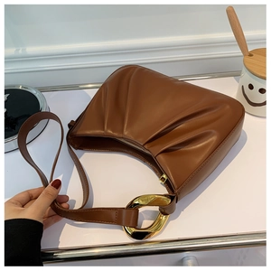 Detail of dark brown pleated cloud bag featuring oversized golden metal ring buckles