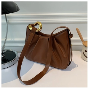 Close-up of brown pleated leather handbag with elegant gold metal hardware buckle
