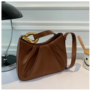 Detail view of caramel brown pleated shoulder bag with golden metallic ring accents