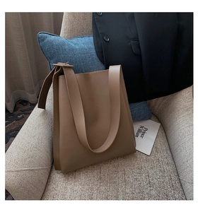 Minimalist large khaki tote bag with wide strap on chair in business casual setting