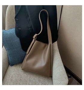 Detail of premium brown leather tote bag with adjustable strap on a minimalist chair