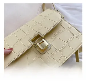 Close-up of beige crocodile embossed leather with a square golden metallic push-lock