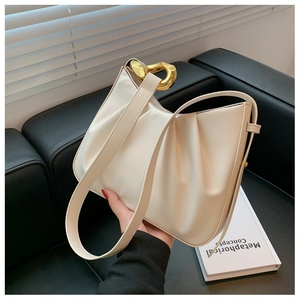 Detailed view of cream ruched bucket bag with unique gold metallic buckle and soft texture