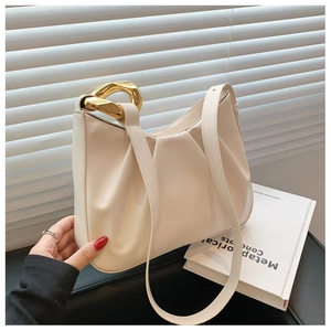 Close-up of beige ruched handbag featuring large gold chain link and textured surface