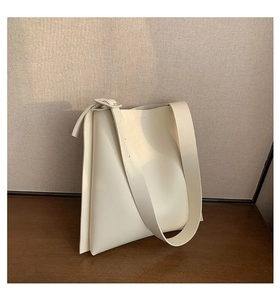 Detail of minimalist cream leather tote bag with smooth texture on a wooden table