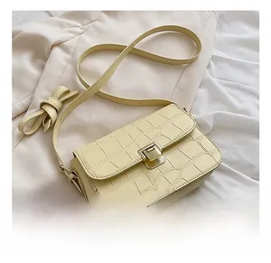 Detailed macro view of crocodile pattern texture and gold metal buckle on beige bag