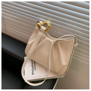Detail of cream pleated cloud bag featuring a thick gold chain handle and soft PU texture