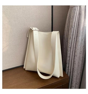 Detail of minimalist cream white tote bag featuring wide shoulder strap and square buckle