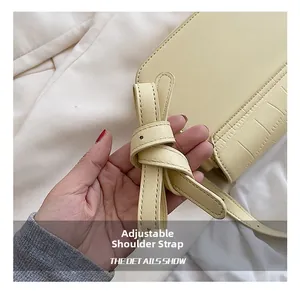 Detailed macro view of adjustable leather shoulder strap on yellow crocodile embossed bag