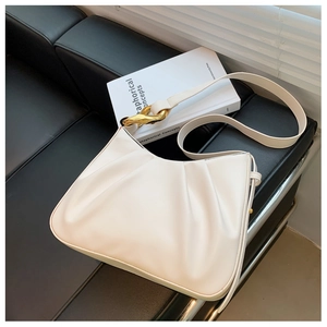 Detail of white pleated hobo bag with gold hardware ring on a leather bench