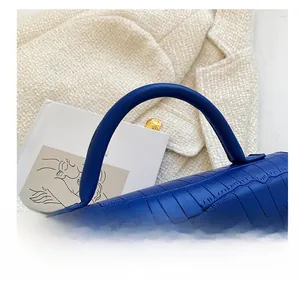 Dettaglio macro del manico rotondo su una borsa blu con elegante motivo a coccodrillo
