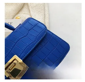 Dettaglio macro della borsa blu reale con stampa coccodrillo e fibbia in metallo oro