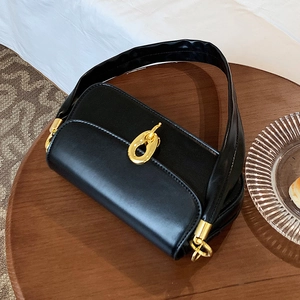 Minimalistische schwarze matte Umhängetasche aus Leder mit goldener Schnalle auf Holztisch