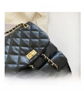 Close-up of black quilted leather backpack with gold metal turn-lock and chain strap