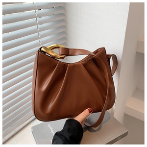 Detail view of brown pleated bucket bag with chunky gold chain and textured PU leather