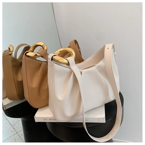 Close-up of ruched cloud bucket bag with chunky gold chain handles and leather straps