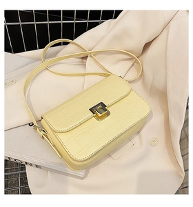 Detail of pale yellow crocodile texture handbag with elegant gold square metal clasp