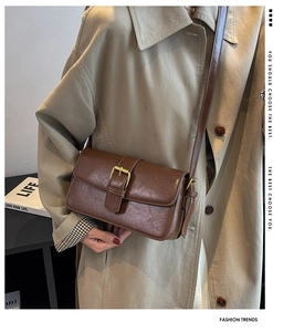 Detail of vintage brown leather crossbody bag with golden buckle and sleek finish