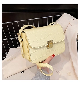 Close-up of pale yellow crocodile embossed leather flap bag with gold twist lock hardware