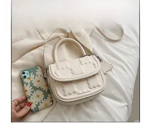 Mini cream crossbody bag with cloud texture next to a smartphone for size comparison