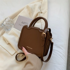 Dark brown structured handbag with wave edge design and adjustable strap on a neutral background