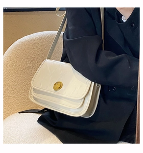 Elegant white quilted crossbody bag with gold rotating lock shown on model's shoulder