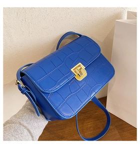 Close-up of royal blue crocodile embossed small square bag with elegant gold metal buckle