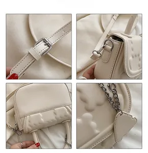 Detail view of cream crossbody bag featuring silver hardware, cloud pattern and heart charm