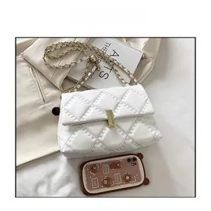 Dettaglio borsa trapuntata bianca con catena dorata e chiusura metallica su un blazer