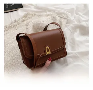Detailed macro view of brown leather bag with golden Q-shaped metal magnetic buckle
