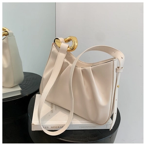 Detail of elegant pleated cream shoulder bag featuring premium gold geometric metal buckle