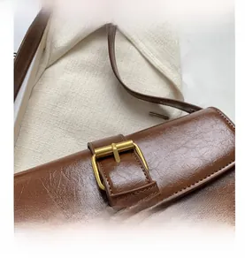 Close-up of brown leather texture and golden pin buckle closure on vintage bag