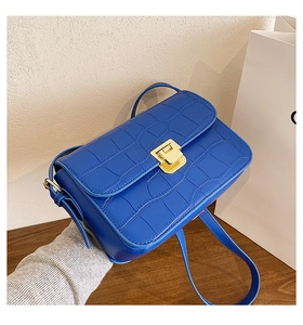 Close-up of bright blue crocodile pattern leather crossbody bag with gold metal clasp