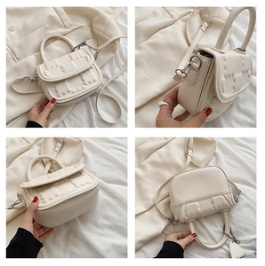 Detail of cream mini crossbody bag featuring 3D embossed bear and heart charm