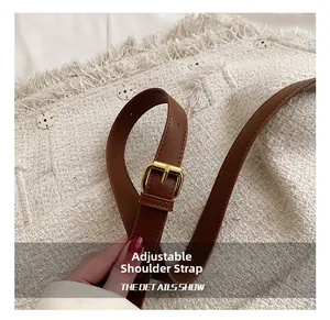 Detail of adjustable brown leather shoulder strap with gold buckle on a tweed handbag
