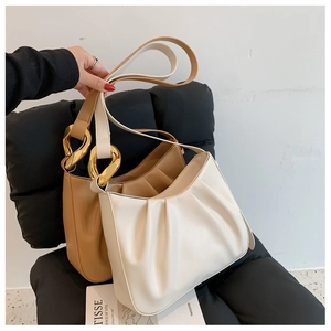 Detailed shot of pleated hobo bags in cream and khaki with gold chunky chain links