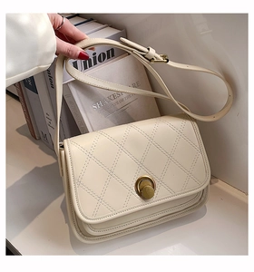 Detail of off-white quilted shoulder bag with golden ring buckle and flap closure