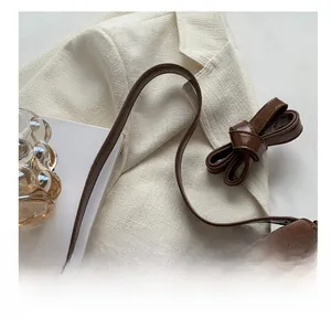 Close-up of vintage brown leather handbag with antique bronze buckle and textured grain