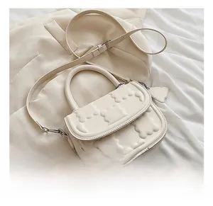Detail of cream crossbody bag with 3D embossed cloud pattern and matching charm